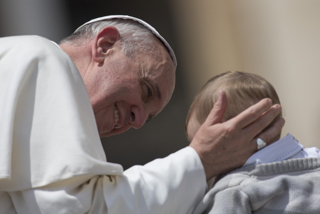 Pope Francis caresses a baby as he leaves at the end of his weekly general audience, in St. Peter's Square, at the Vatican, Wednesday, May 29, 2013. The rain hasn't stopped Pope Francis. The 76-year-old pontiff, who lost part of a lung during his youth to an infection, got soaked Wednesday as he braved a brief spring shower to kiss babies and greet crowds at his weekly general audience in St. Peter's Square. Zooming around the piazza in his open-air jeep, Francis had no umbrella or cover over him as he made his way through a sea of brightly colored umbrellas, happily stopping to caress and kiss babies handed up to him. (AP Photo/Andrew Medichini)