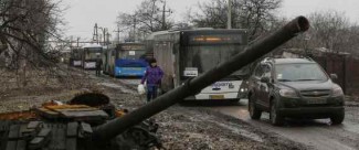 Empty buses, intended for internally displaced persons (IDPs), wait along a road beside a burnt-out tank turret while travelling in the direction of the village of Debaltseve to evacuate the residents, in Vuhlehirsk, Donetsk region