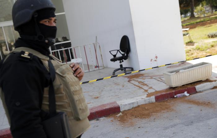 A policeman guard the entrance of the Bardo museum in Tunis, Tunisia, Thursday, March 19, 2015, as a a blood stain is seen at right,  a day after gunmen opened fire killing over 20 people, mainly tourists. One of the two gunmen who killed tourists and others at a prominent Tunisian museum was known to intelligence services, Tunisia's prime minister said Thursday. But no formal links to a particular terrorist group have been established in an attack that threatens the country's fledgling democracy and struggling tourism industry. (ANSA/AP Photo/Christophe Ena)