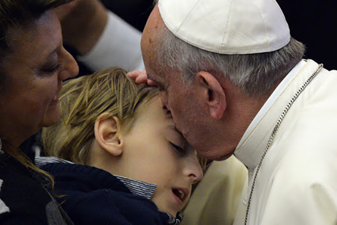 Pope Francis kisses a child during a meeting with blind and deaf people at Paul VI audience hall on March 29, 2014 at the Vatican.  AFP PHOTO / ANDREAS SOLARO