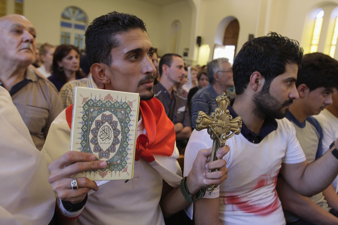 An Iraqi man carrying a cross and a Koran attends a mass at Mar Girgis Church in Baghdad