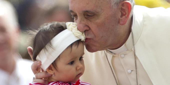 Papa Francesco bacia una bimba ANSA/CLAUDIO PERI